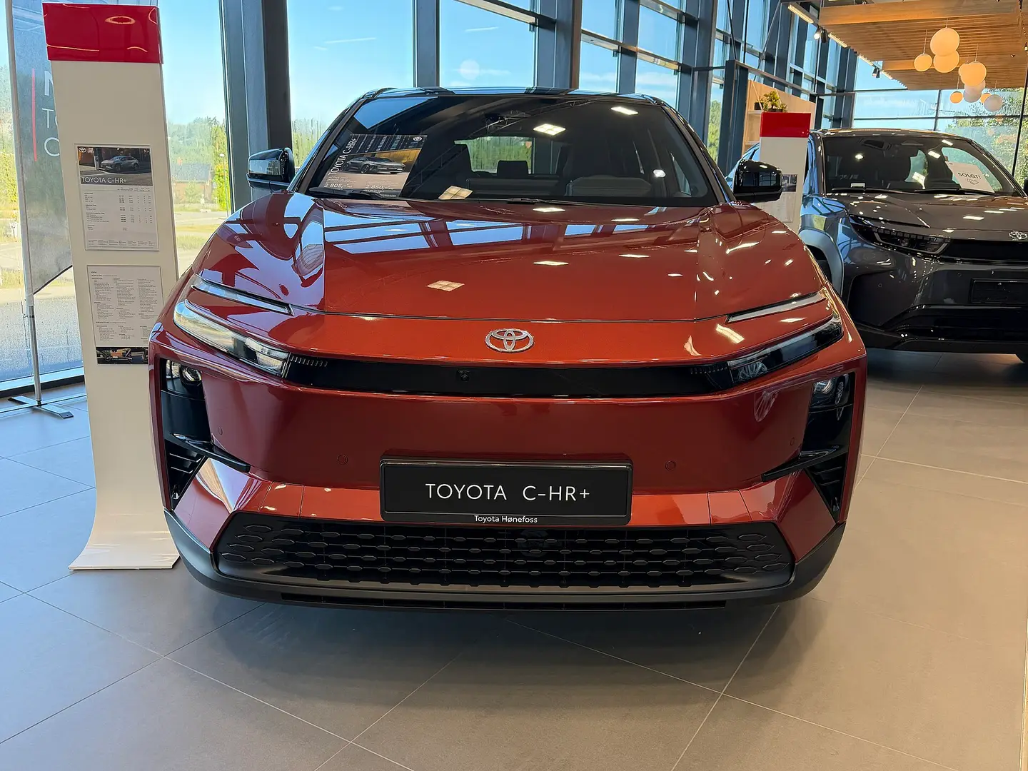 Toyota C-HR+ rojo de frente en un concesionario
